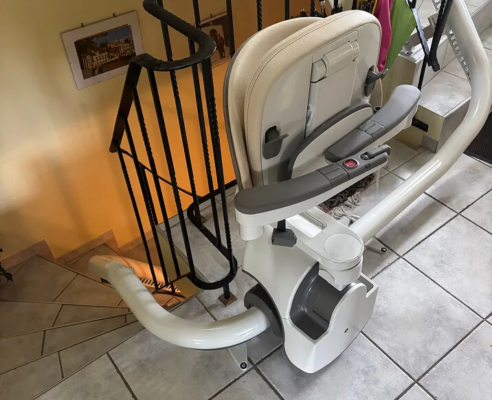 Treppenlift auf gewendelter Treppe mit schmiedeeisernem Geländer